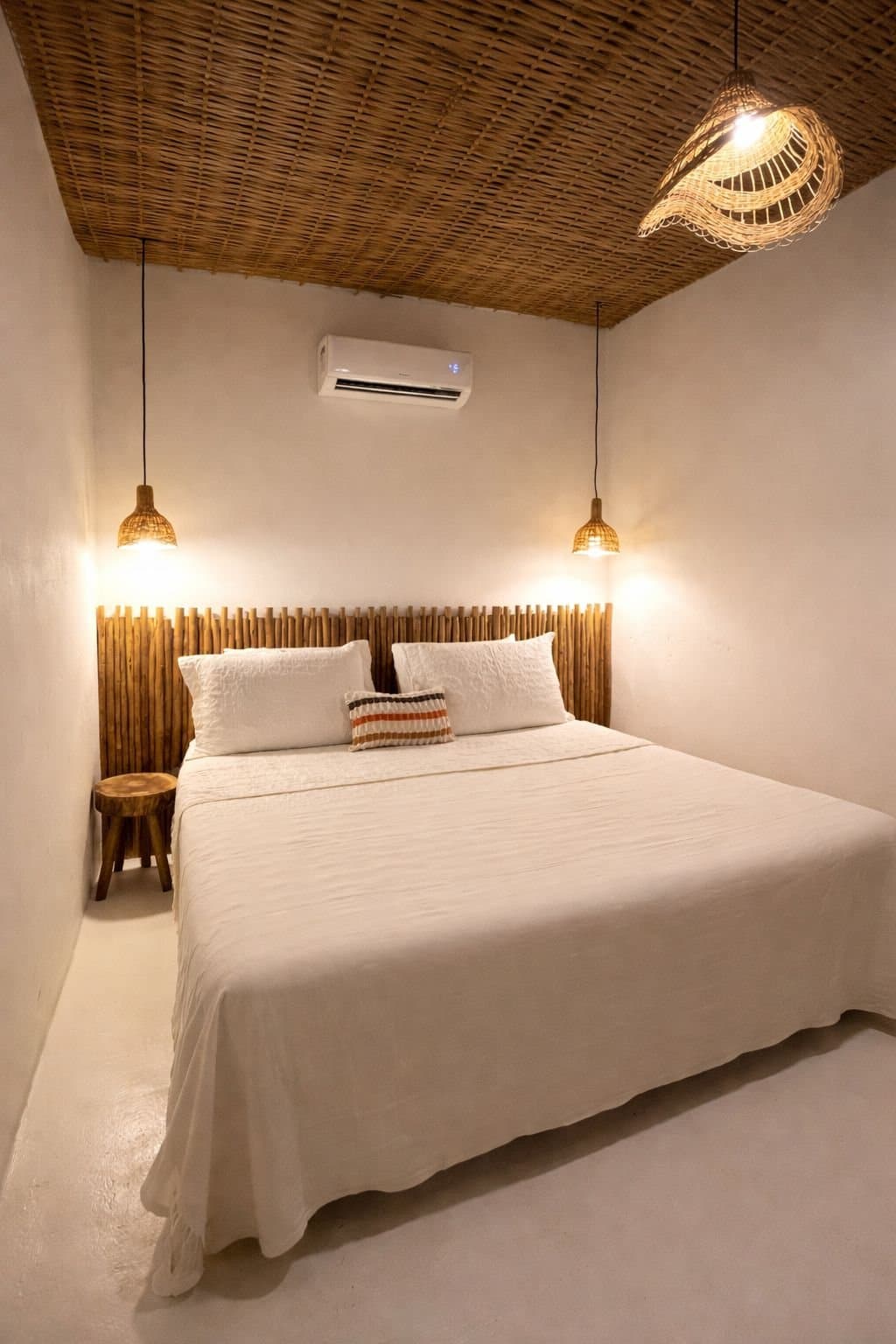 Suíte com cama de casal, cabeceira de bambu, teto de palha trançada e ar-condicionado na parede