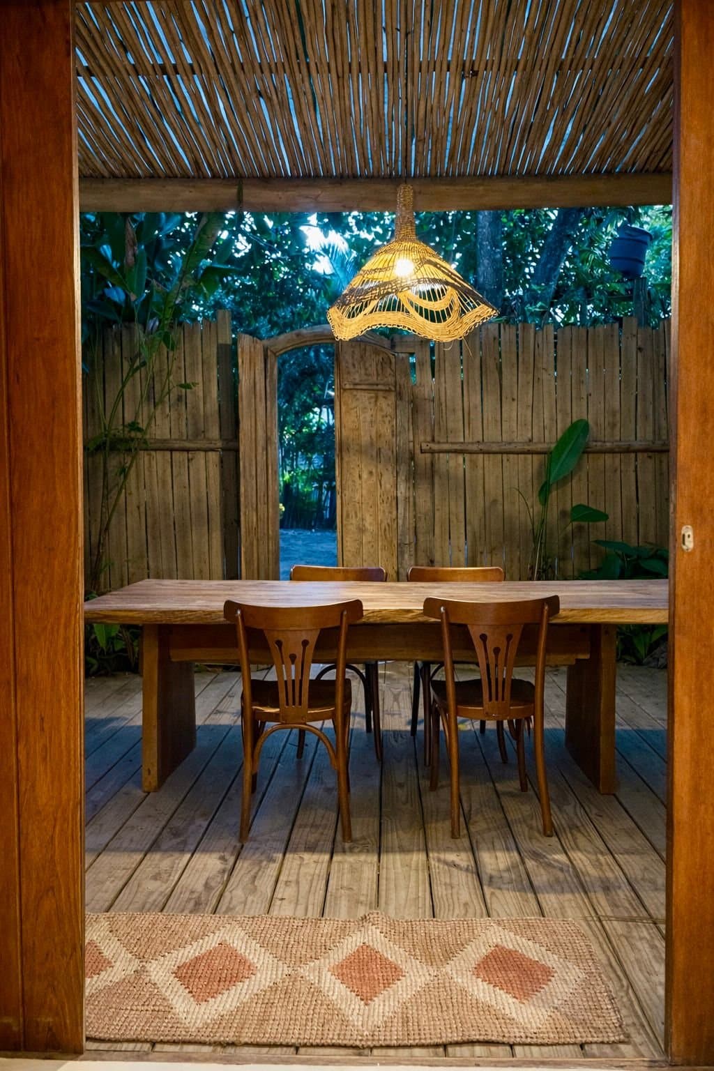 Mesa de jantar de madeira no deck coberto, vista da porta da sala