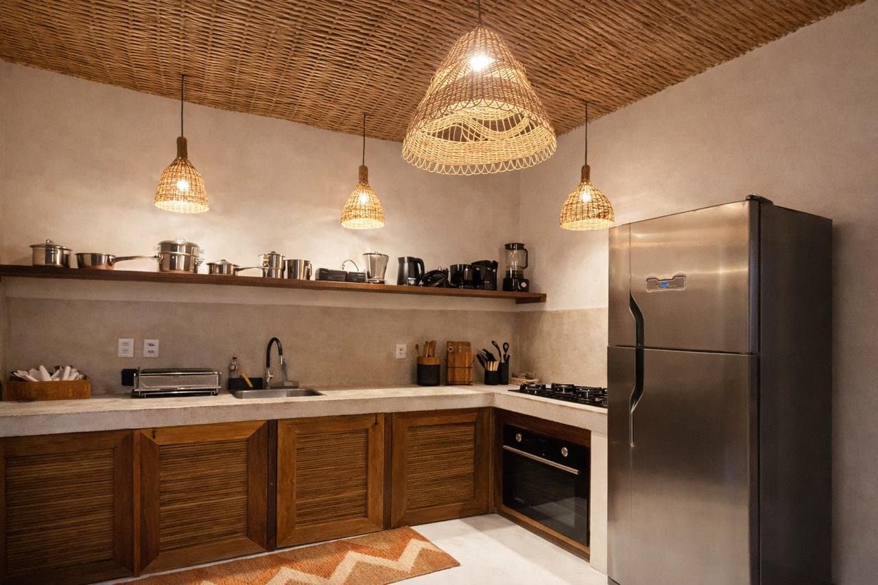Cozinha com fogão, forno, geladeira e luminárias de fibra sobre a bancada